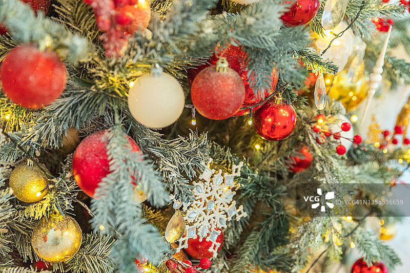 经典的圣诞新年用红色、金色和白色的装饰品装饰圣诞树，玩具和球。现代古典风格的室内设计公寓。平安夜在家图片素材