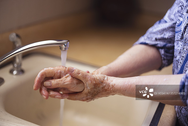 老妇人在厨房水槽边洗手图片素材