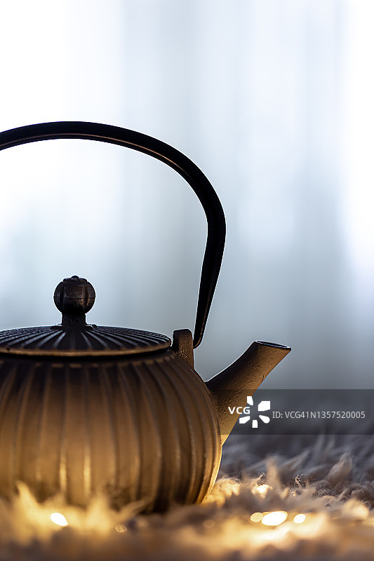 茶壶在黑暗中模糊的背景和花环。图片素材