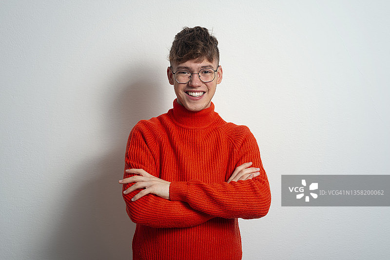戴着眼镜和红毛衣的微笑的年轻人图片素材