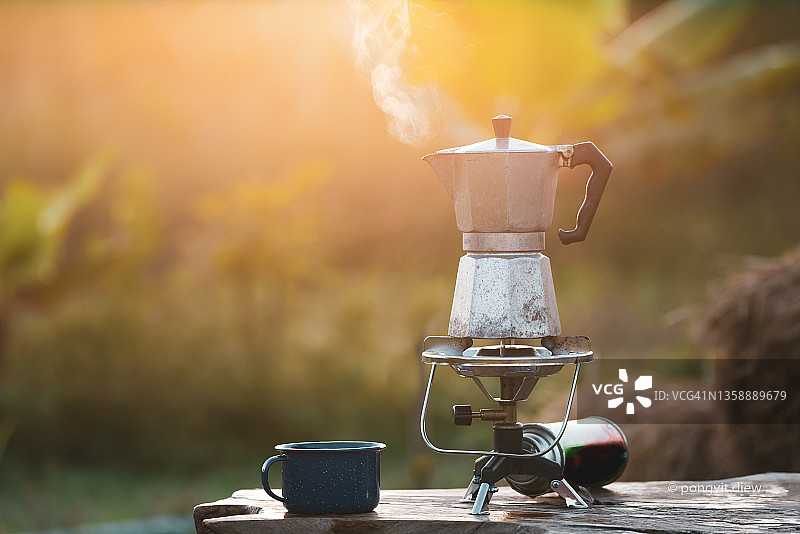 古董咖啡壶在早上太阳升起的时候放在煤气炉上供露营用。软的焦点。图片素材