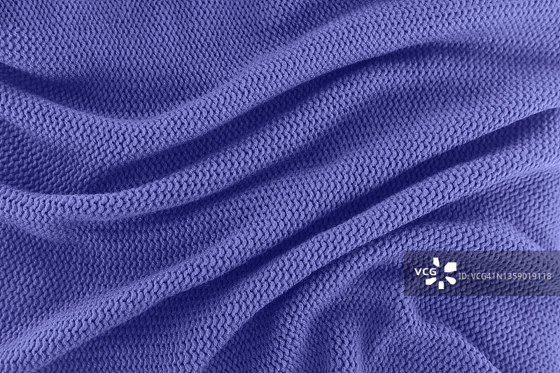 质地的针织紫色毛衣折叠成漩涡图案。平铺风格，特写。展示了2022年的颜色。图片素材
