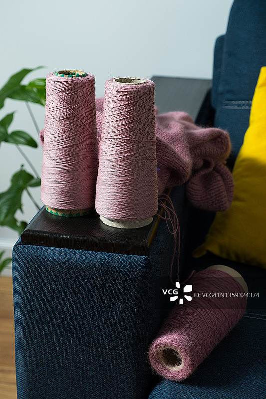 一个松散的毛衣针织项目和金属针织针，特写。在房间里，在家里的沙发上，粉红色的毛线，线和球。爱好、创意、针线活和手工的概念。用自己的双手创造衣服。图片素材