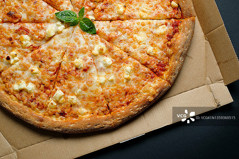 意大利披萨在披萨盒和外卖，在白色背景或桌子上。玛格丽塔披萨加番茄和奶酪，切成块，不加肉。素食概念，快餐不健康食品。送货上门或上班。副本的空间。图片素材