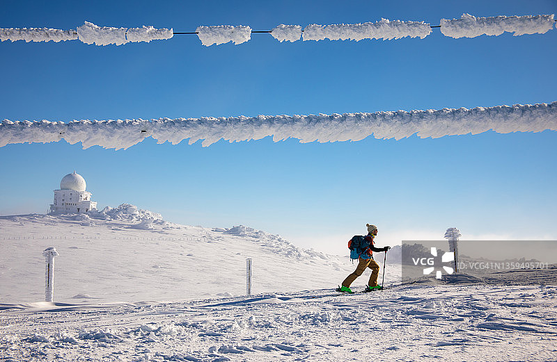 在一个寒冷的冬天，一个滑雪爱好者在爬山图片素材