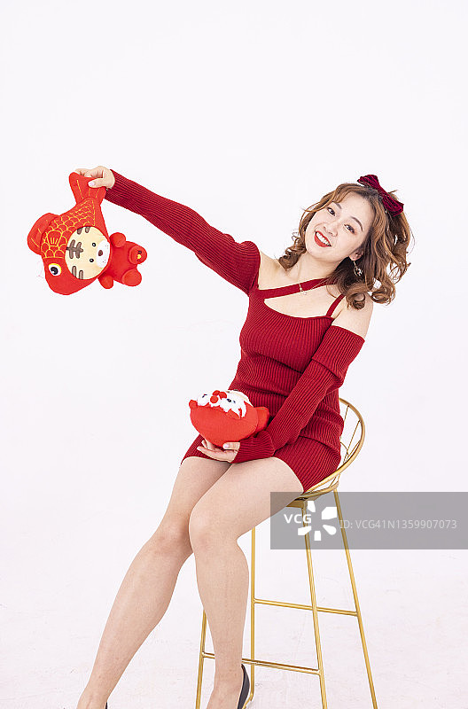 快乐的年轻女子用红虎娃娃庆祝中国新年图片素材