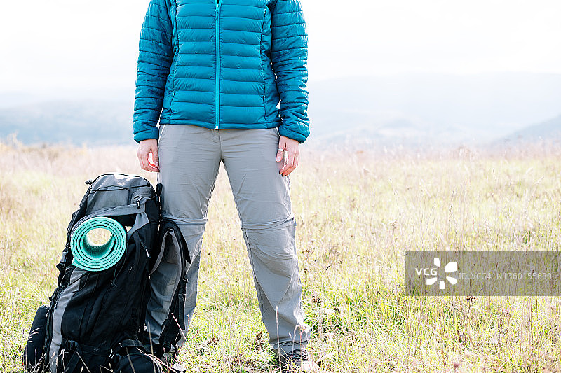 一个不认识的人站在小山中间，她的旅行背包靠在腿上图片素材