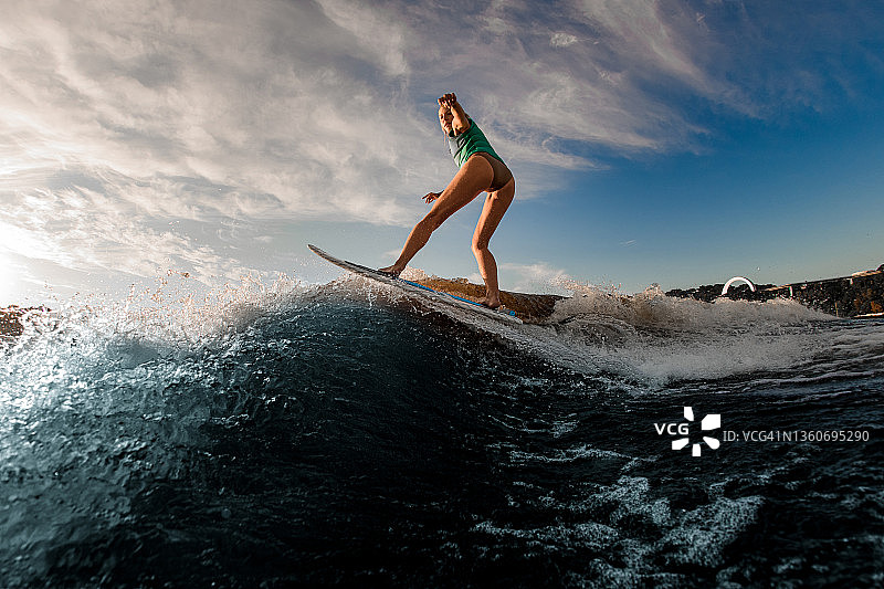 年轻迷人的女子熟练地平衡在水上飞溅的波浪图片素材