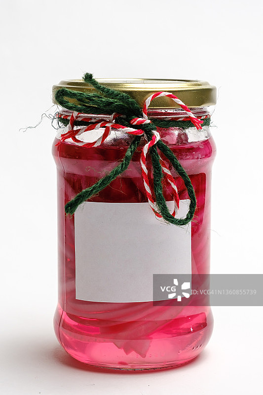 一罐腌红洋葱。装饰有红、绿、白三种颜色的麻线和有光泽的标签。孤立与白图片素材