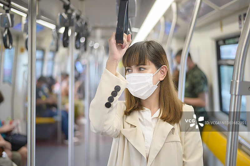 年轻女性在地铁、新冠肺炎防护、安全出行、新常态、保持社交距离、安全出行、大流行理念下佩戴防护口罩图片素材