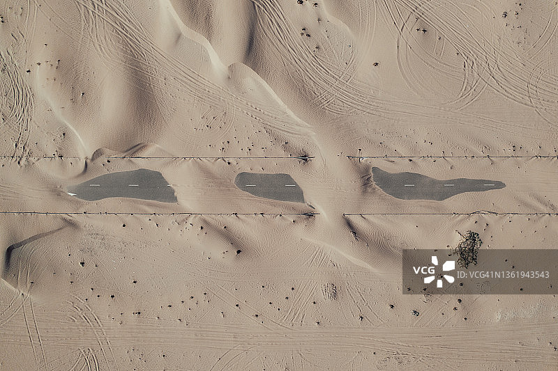 阿拉伯联合酋长国迪拜，从空中俯瞰，沙漠中覆盖着一条道路的沙子图片素材