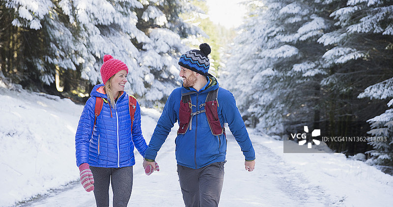 情侣手牵着手，在雪原林中徒步旅行图片素材