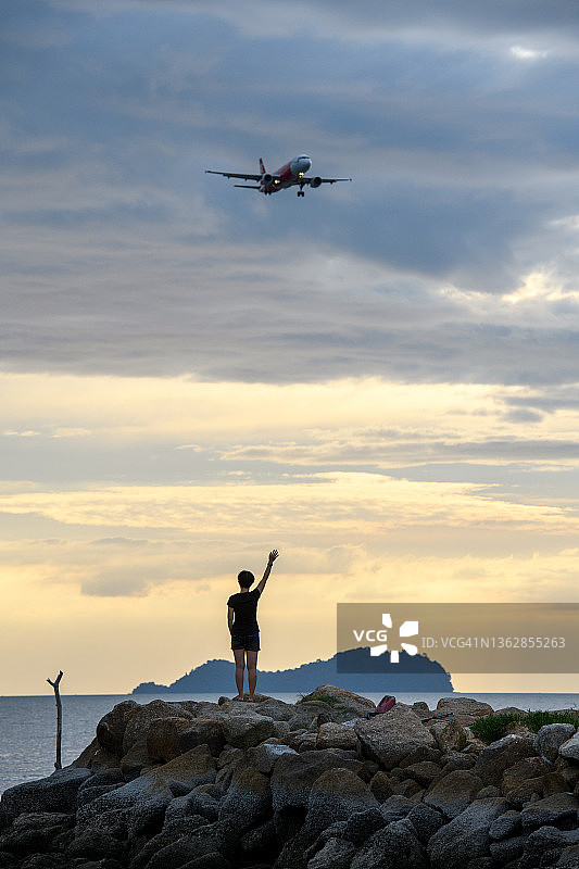 一位女士向一架经过的飞机挥手致意图片素材
