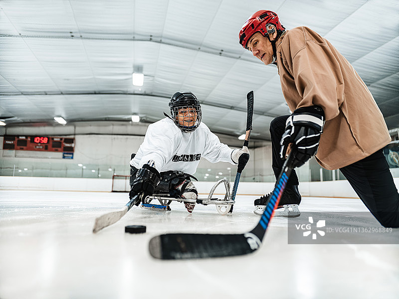 成熟的残疾人拉丁妇女和她的教练练习雪橇曲棍球图片素材