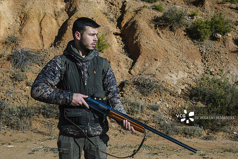 男性猎人的肖像，握着枪和寻找新的猎物，而狩猎在野外。图片素材