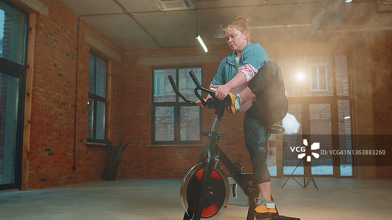 健康的白人妇女锻炼锻炼在健身器脚踏车在健身房，慢动作图片素材