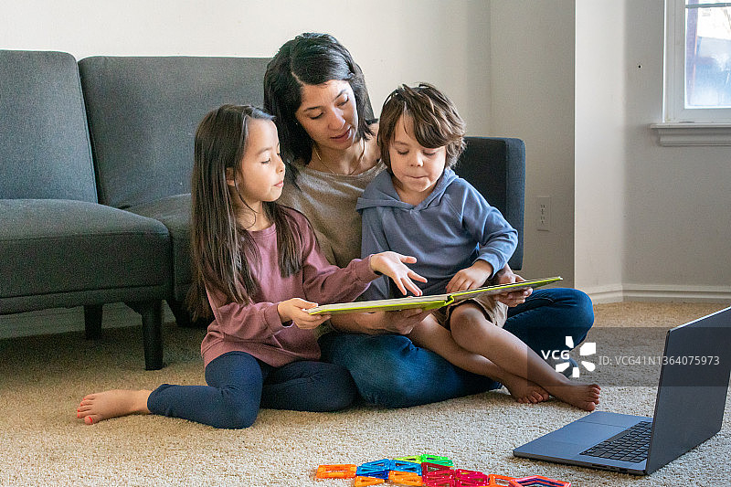 一位母亲和她的孩子们坐在客厅里玩笔记本电脑图片素材