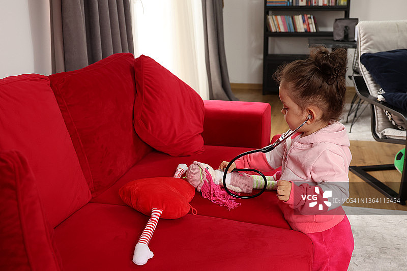 用听诊器听玩具的女孩在玩医生游戏图片素材