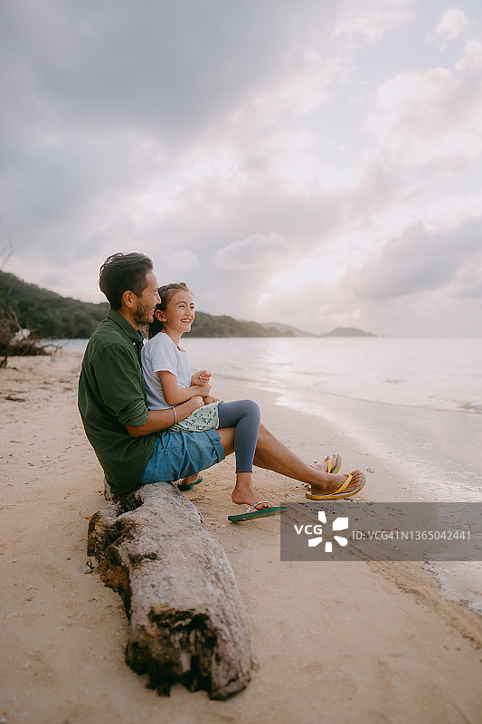 日落时分，日本，父亲和小女儿坐在海滩上图片素材