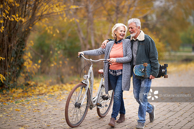 快乐的老年夫妇在公园里享受秋天的散步。图片素材