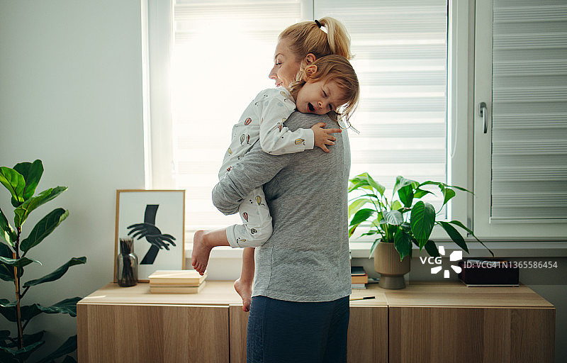 瞌睡时间:早上妈妈抱着她瞌睡的女儿图片素材