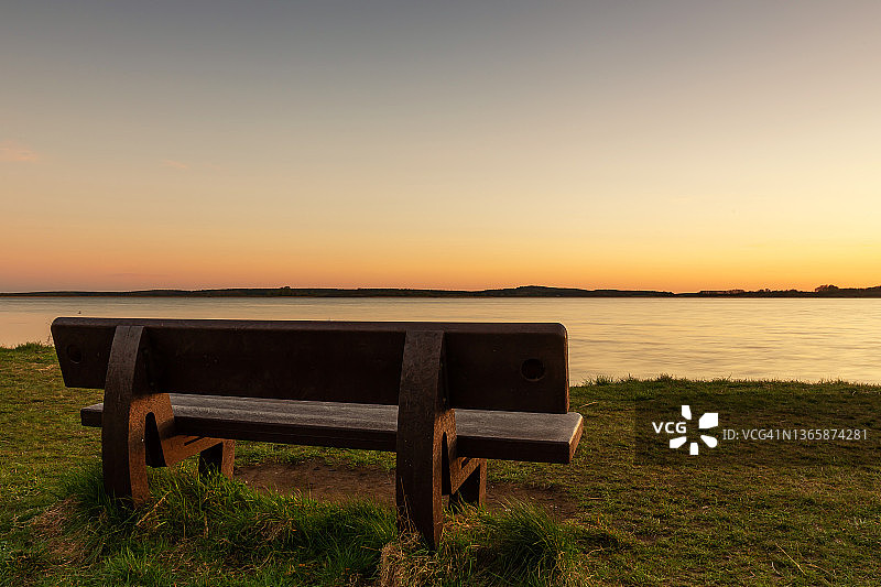 日落时坐在湖边的长椅上图片素材