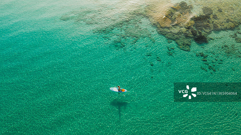 希腊扎金索斯岛，男子在碧绿的海面上用桨冲浪的鸟瞰图图片素材