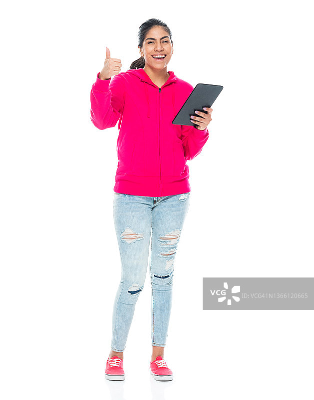 z一代年轻女性站在白色背景前，穿着帆布鞋，使用数码平板电脑图片素材