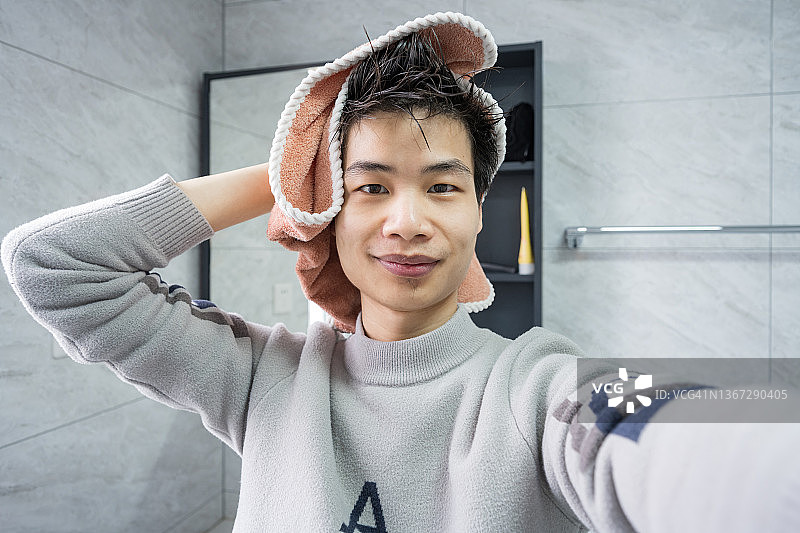 一个快乐的年轻男性用毛巾擦干头发的肖像图片素材