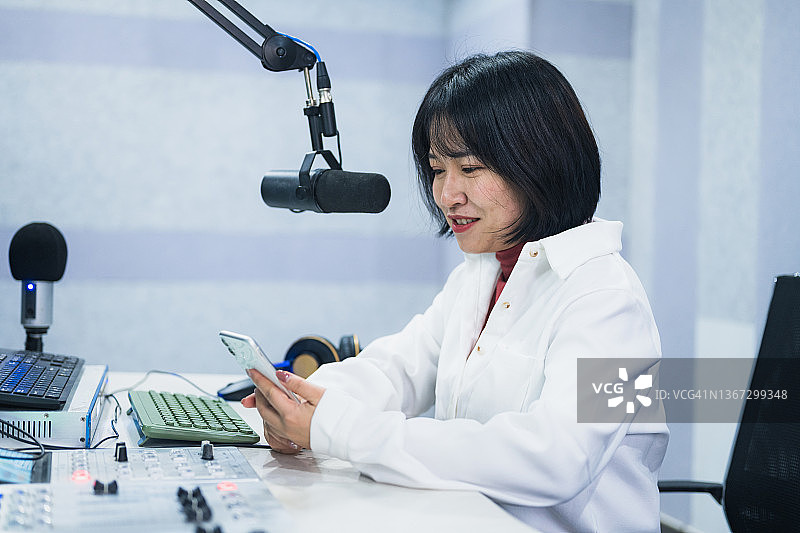 一位年轻的亚洲女性主持人在一家电台的现场工作图片素材