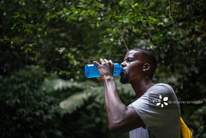 一个中年男子在森林里喝水图片素材