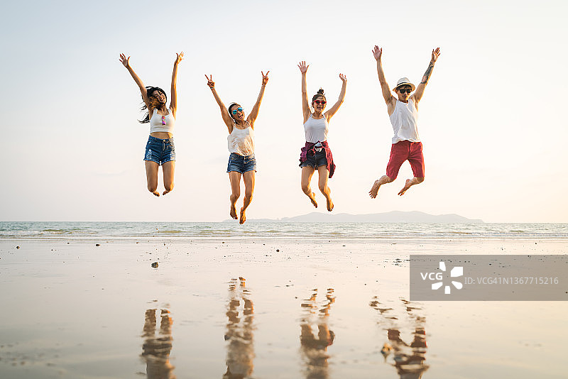 一群亚洲朋友在沙滩上连续跳跃，享受夏日假期图片素材