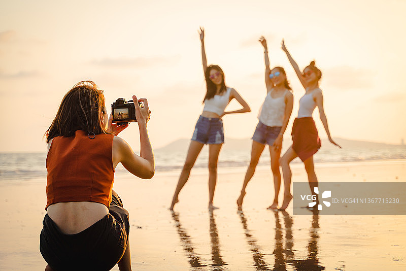 一群亚洲朋友一起在海滩上享受周末的照片图片素材