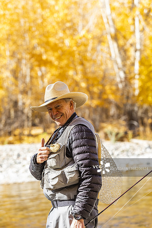 美国，爱达荷州，贝尔维尤，微笑的老人在秋天的大木河飞钓的肖像图片素材
