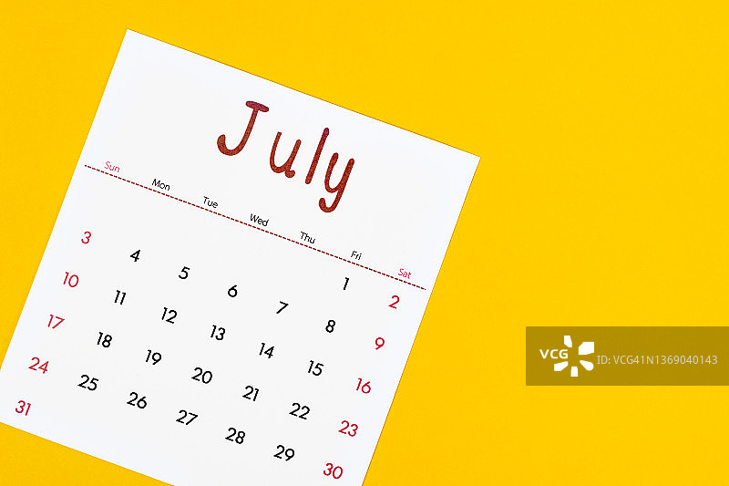 7月是组织者计划和提醒的月份，用黄色的纸做背景。商业计划预约会议概念图片素材