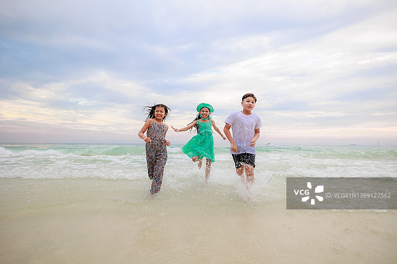 一群孩子在沙滩上奔跑。夏日、假期、休闲的概念。图片素材