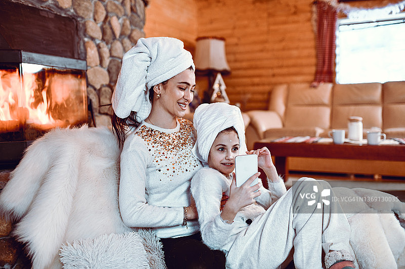 在山间小屋，母亲和女儿沐浴后拥抱的自拍时间图片素材