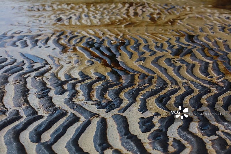 海洋和海滩被石油污染了。原油泄漏在城市海滩的沙滩上图片素材