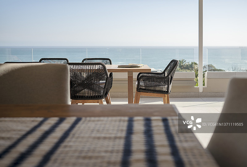 在阳光明媚的豪华露台上，餐桌和椅子后面的海景图片素材
