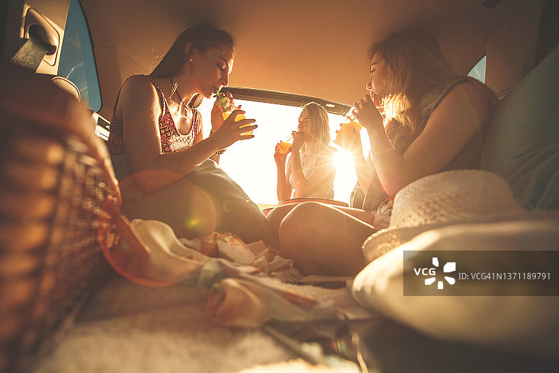 闺蜜们在自驾游和野营时在汽车后备箱里玩得很开心图片素材