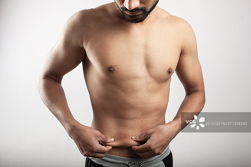 健身男子通过伸展皮肤显示腹部脂肪图片素材