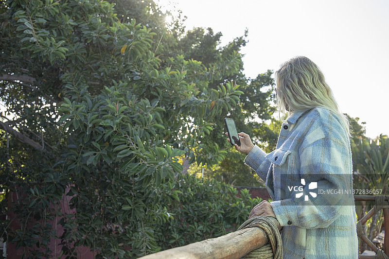 一名女子用手机拍摄雨林照片图片素材