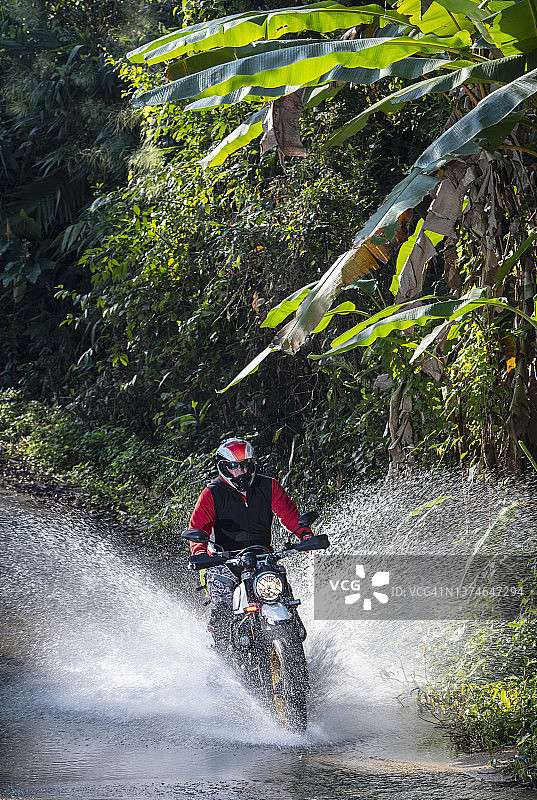 泰国，一名男子骑着他的扰频器式摩托车穿越河流图片素材