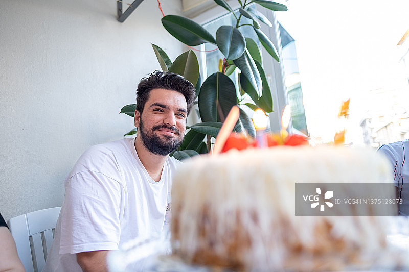 年轻英俊的男子微笑着看着他们家的生日蛋糕图片素材