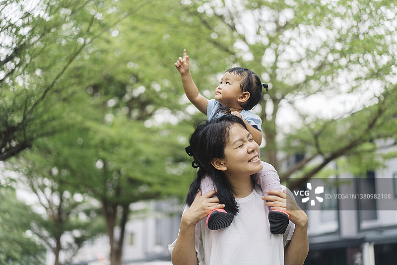 积极情绪亚洲母亲背女儿休闲户外公共花园周末活动图片素材