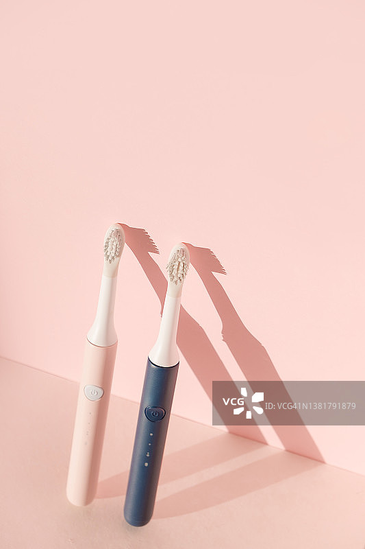 两把新型超声波牙刷。牙科护理用品粉红色粉彩背景。口腔卫生，牙齿和牙龈健康，牙齿健康。牙科产品超声波振动牙刷图片素材
