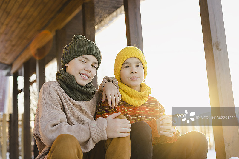 冬天，小男孩和哥哥坐在屋前微笑图片素材