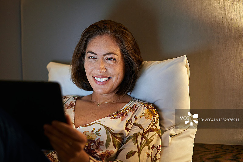 女性在酒店房间的床上使用数码平板电脑图片素材