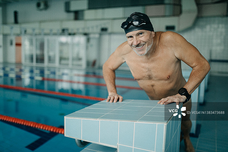 老年人游泳运动员在公共游泳池室内做热身运动。图片素材