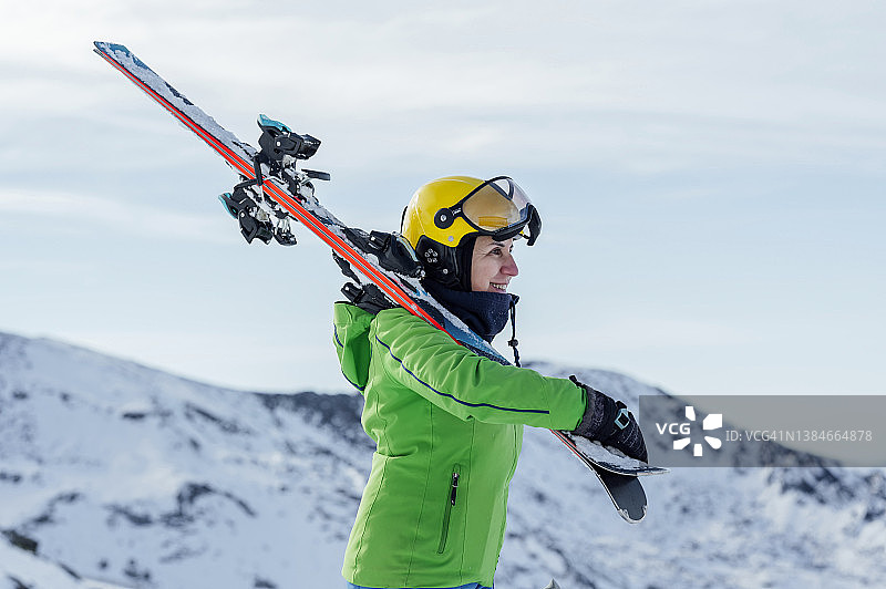 中年妇女滑雪者扛着滑雪板在山上行走图片素材